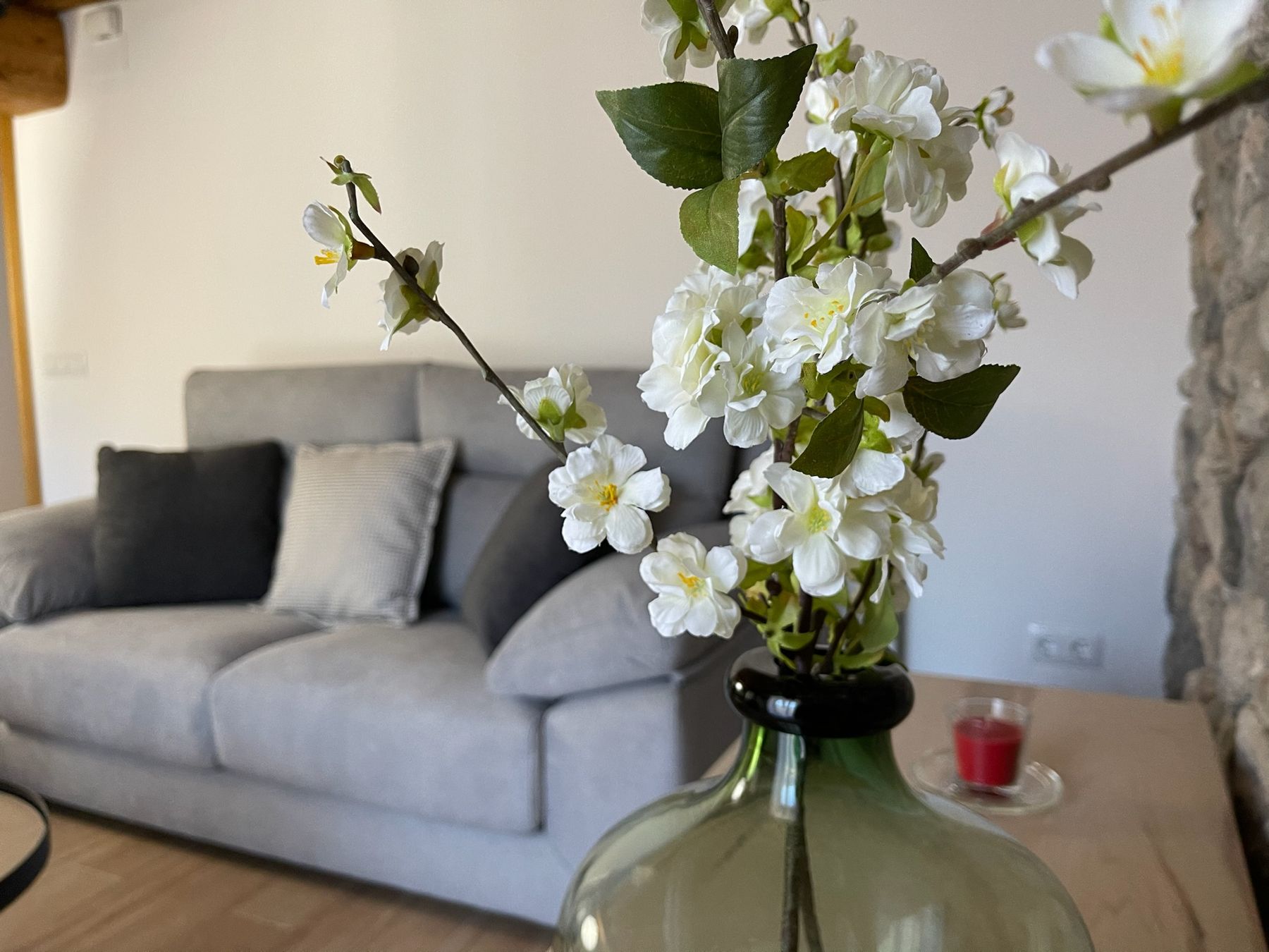 Detall de la sala amb flors i el sofà al fons