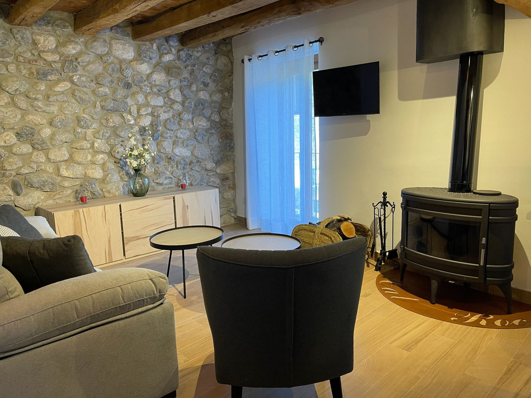 Sala d'estar amb estufa de llenya i paret de pedra